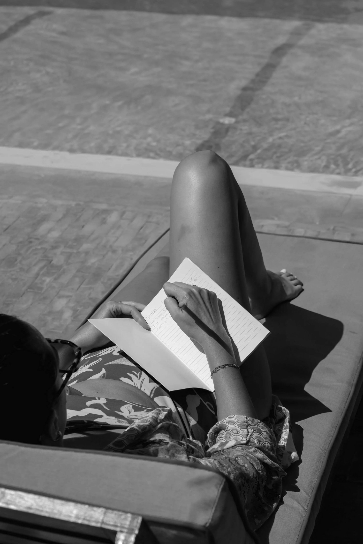 A RYMER journaling on a sun lounger by the water